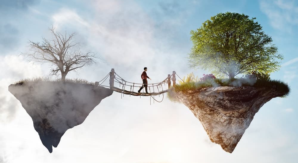 Ein Mensch macht einen Schritt in eine neue, bessere Welt über eine Brücke, die trostloses Land mit einer grünen Insel verbindet.