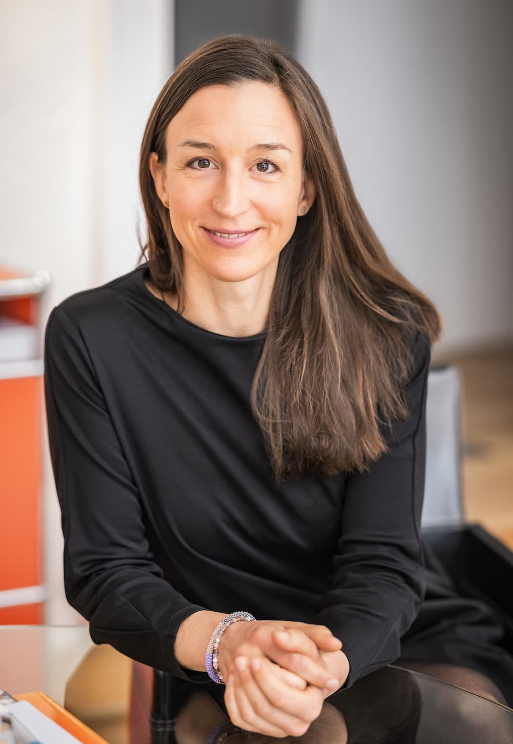 Psychotherapeutin Hannah Adenauer am Glastisch sitzend in einem schwarzen Kleid.
