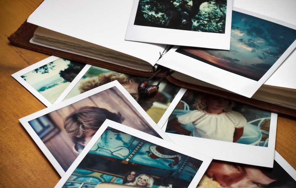 Ein Stapel alter Fotos und ein Tagebuch, um Erinnerungen an vergangene Zeiten zu dokumentieren.
